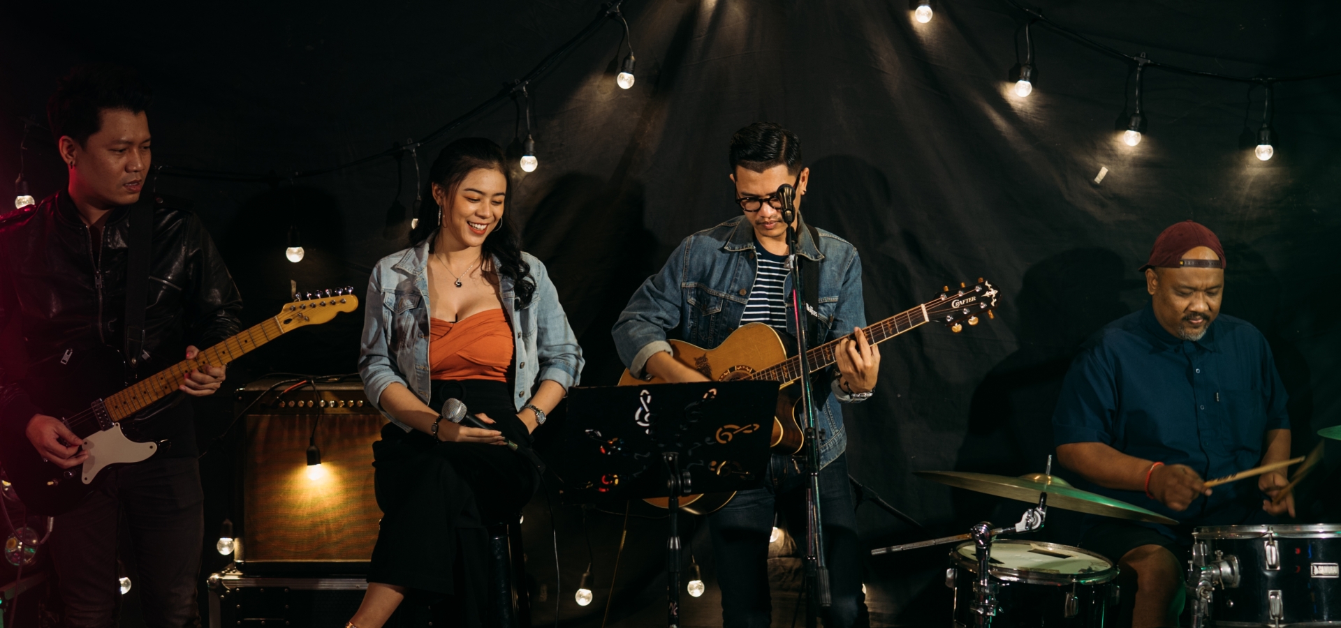 a band playing guitars, and drums and a girl with a microphone in her hand