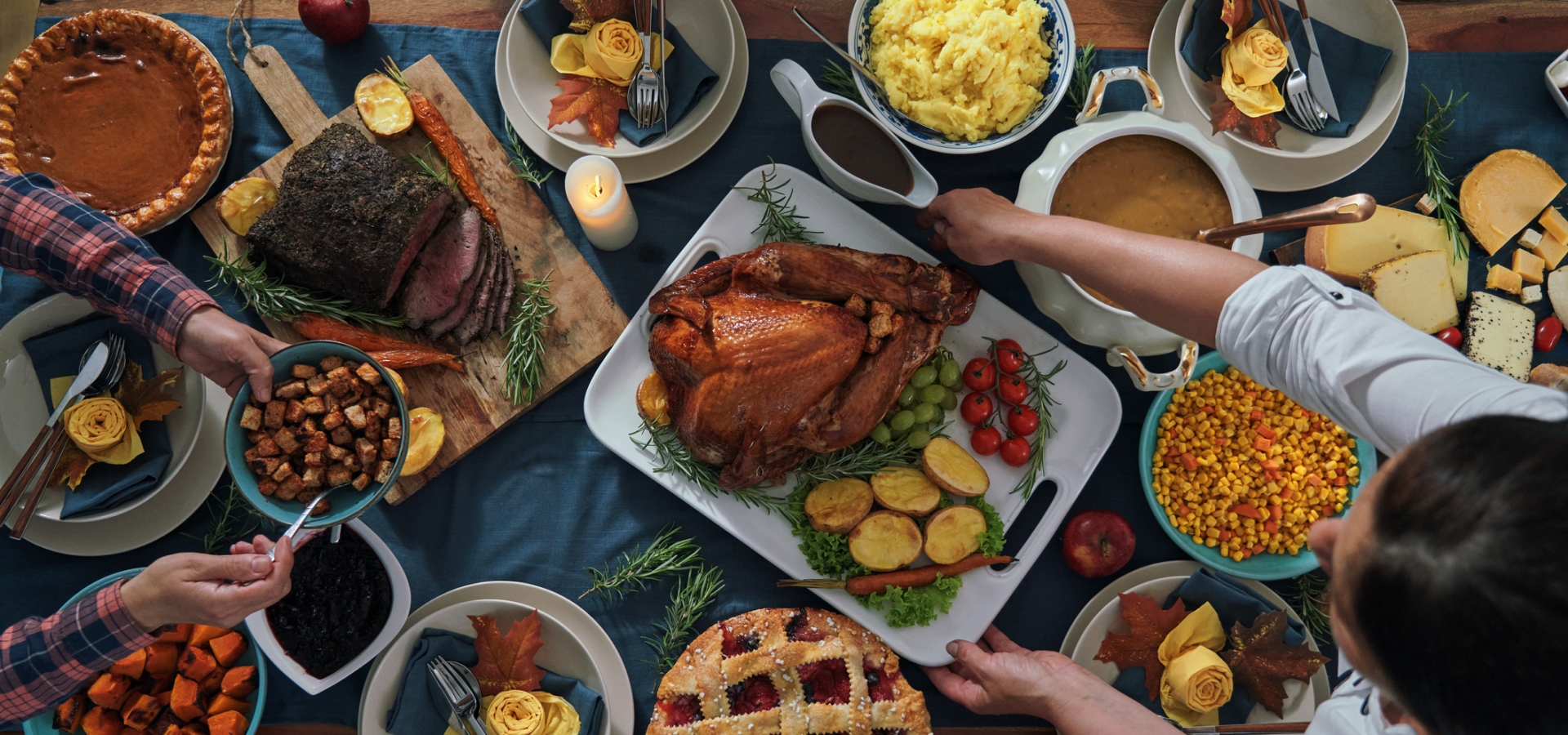 Thanksgiving feast spread out on a table with a family sitting around passing food