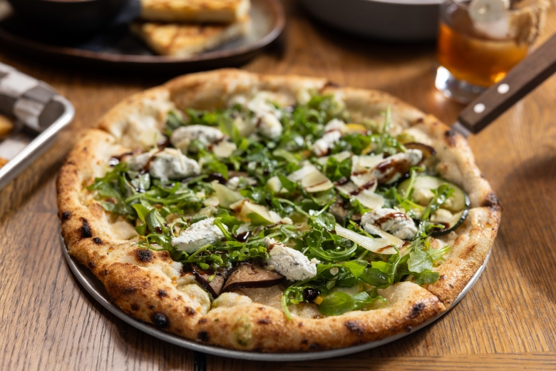 Close up of the Harvest Pizza. Pizza with arugula, chunks of cheese, squash, and zucchini