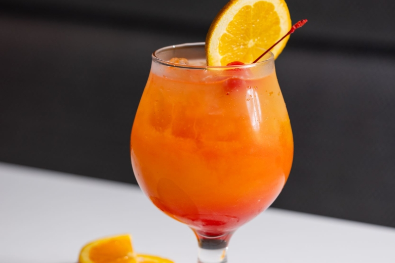 Rum Punch cocktail with and orange wheel and cherry flag as a garnish